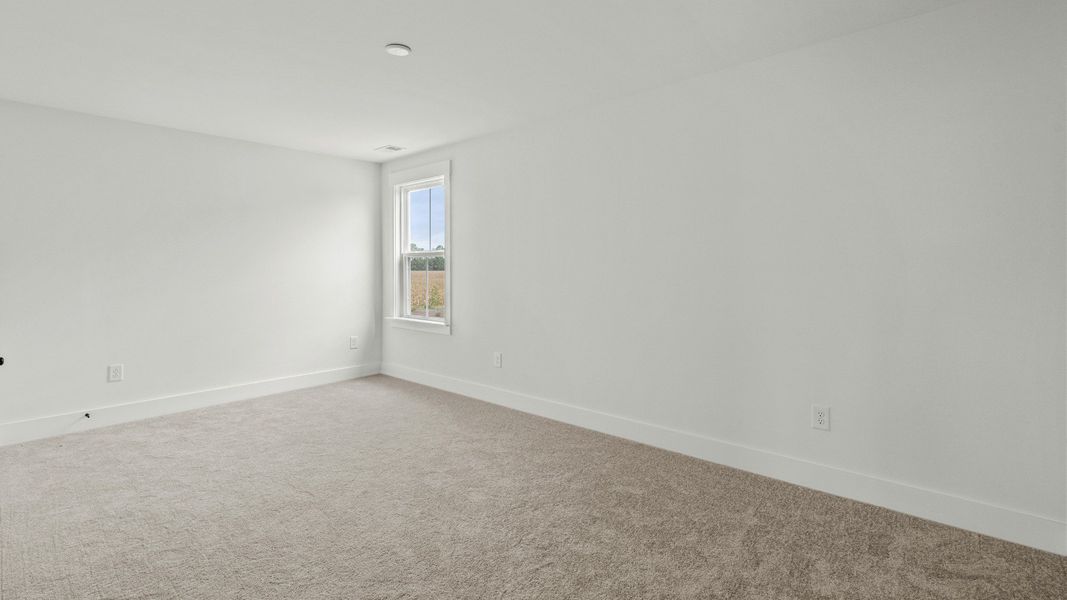 Bright upper-level bedroom with ample space at Chestnut Farms by DRB Homes