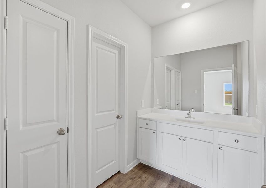 Hallway area featuring the laundry closet doors and a glimpse of the Bath 2 vanity through its open door.