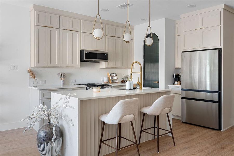 Contemporary kitchen featuring a center island with bar seating, white countertops, extensive light-colored cabinetry, stainless steel appliances, and wood-finish flooring