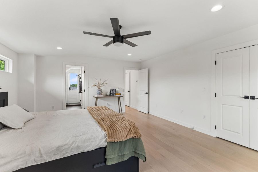Another view of the primary suite, highlighting the ample wall space for a king-sized bed and the sleek, modern ceiling fan that provides both style and airflow.