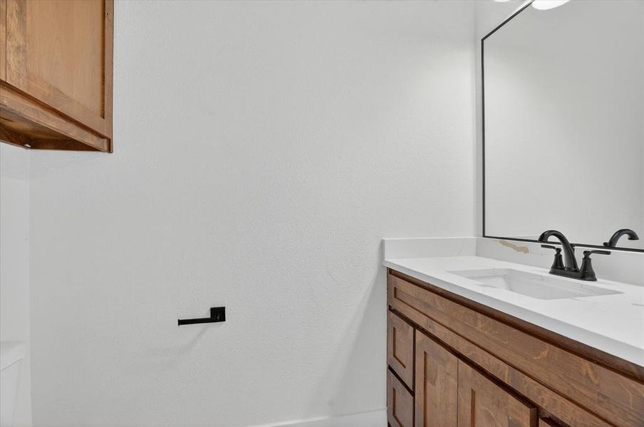 Bathroom vanity featuring a white countertop, under-mount sink, and dark bronze faucet
