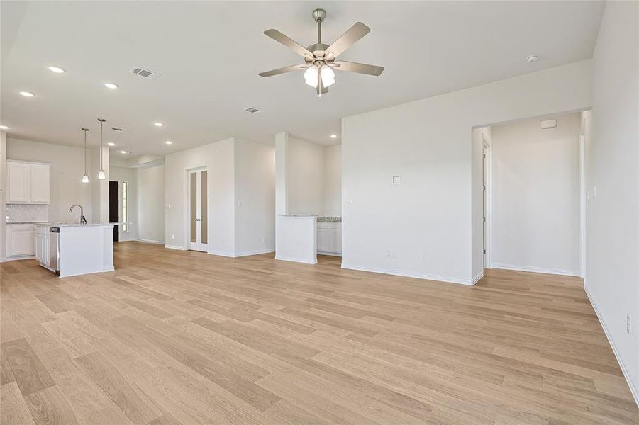 Unfurnished living room featuring ceiling fan, light hardwood / wood-style flooring, and sink