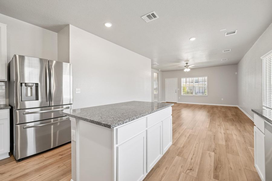 Kitchen featuring stainless steel fridge, a center island, ceiling fan, light wood finished floors, and recessed lighting Kitchen featuring stainless steel fridge, a center island, ceiling fan, light wood finished floors, and recessed lighting