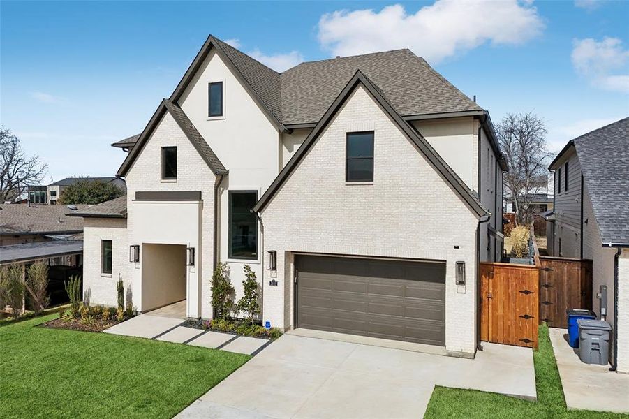 View of front of property featuring brick siding, a gate, concrete driveway, an attached garage, and a shingled roof
