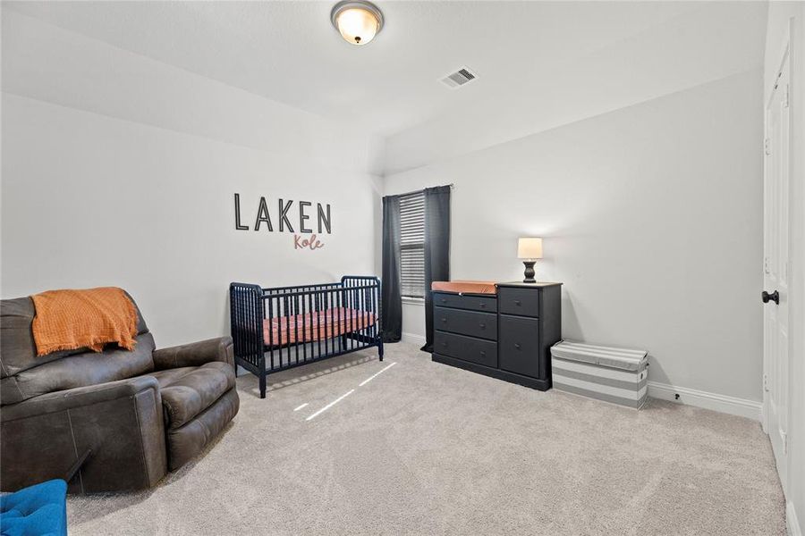 This is a cozy, well-lit bedroom  and neutral walls with carpet and has a window with blinds for natural light control.