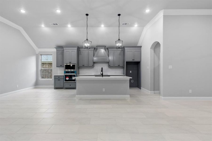 Kitchen featuring gray cabinets, lofted ceiling, crown molding, and appliances with stainless steel finishes