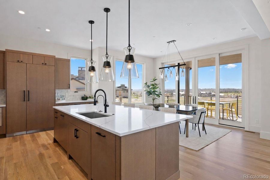 At the heart of the home, the chef’s kitchen is appointed with a full Thermador appliance suite, custom Kitchen Showcase cabinets, Zephyr beverage cooler, quartz counters, and contemporary fixtures.