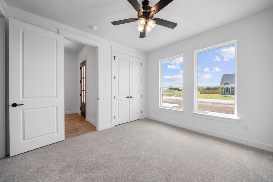 Unfurnished bedroom featuring light carpet, ceiling fan, and a closet