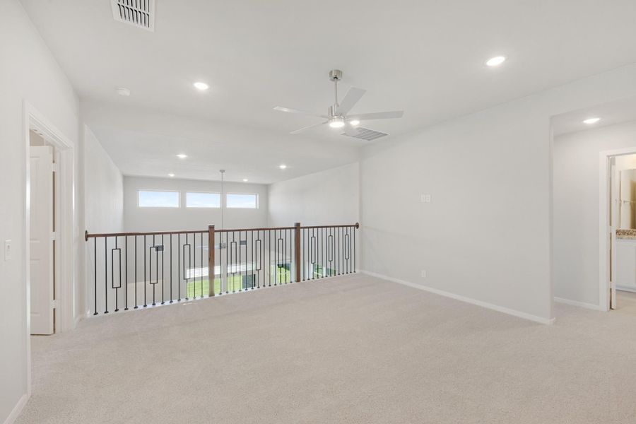 Open upstairs loft with carpet, ceiling fan, recessed lighting, and metal stair railing overlooking lower level Open upstairs loft with carpet, ceiling fan, recessed lighting, and metal stair railing overlooking lower level