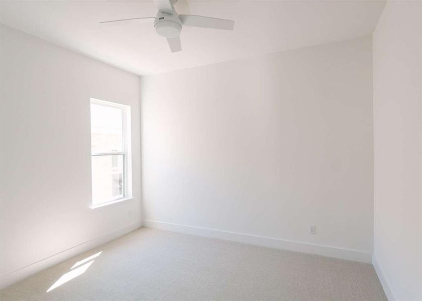 Carpeted empty room featuring ceiling fan