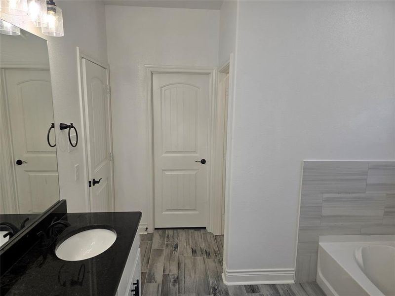 Bathroom with a tub to relax in, vanity, and hardwood / wood-style flooring