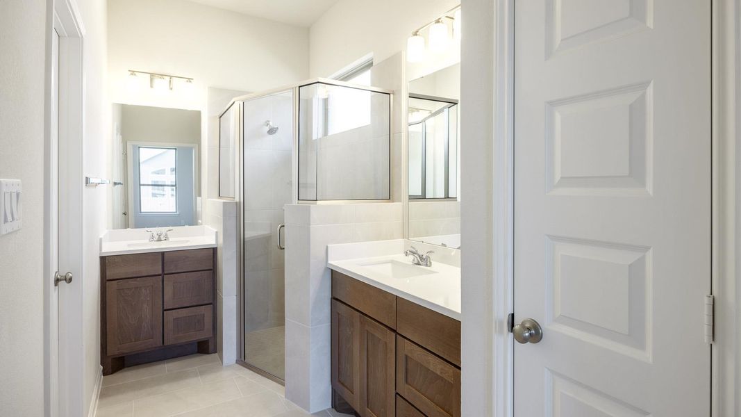 Full bath featuring two vanities, a sink, and a stall shower
