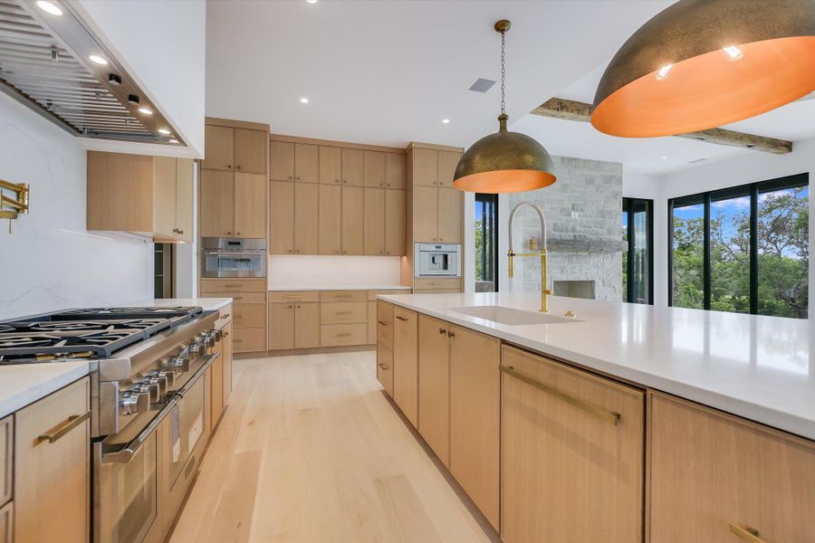 A gourmet kitchen boasts light wood cabinetry, a substantial island, and modern stainless steel appliances.