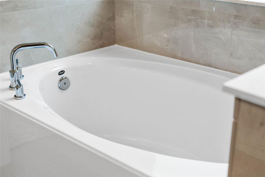 Indulge in the primary bath's deep, built-in soaking tub with elegant chrome fixtures and a sleek tile surround for a true spa-like retreat.