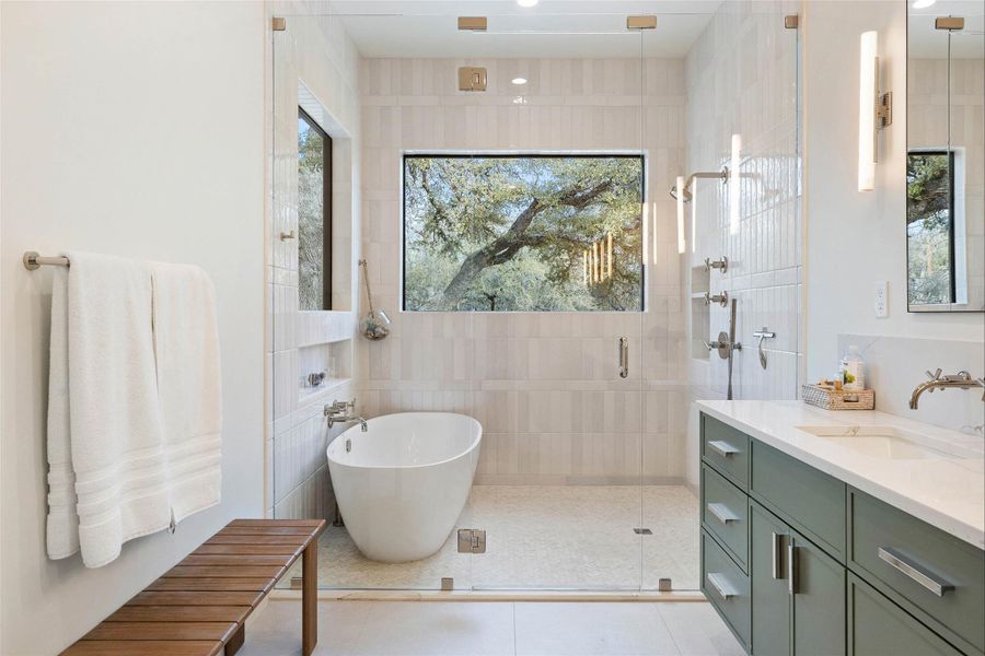 Full bathroom with a shower stall, vanity, a freestanding tub, light tile patterned floors, and healthy amount of natural light