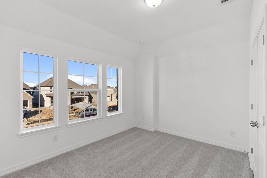 Fourth bedroom with private bath, walk-in closet, plush carpet, and a large window—perfect for guests or an in-law suite.