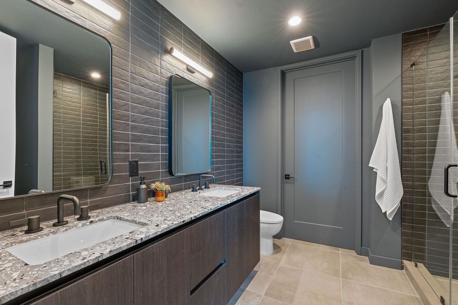 Representative Photo. Primary Bath with spacious double vanity, floor to ceiling tile, and a walk in shower