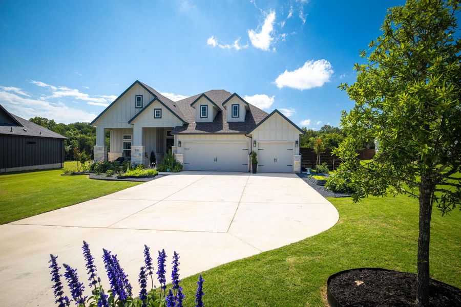 A graceful home featuring dormer windows and an attached garage awaits.