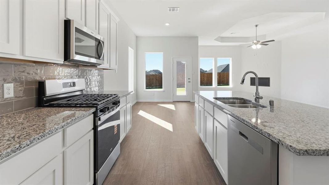 Kitchen with stainless steel appliances, dark wood-style floors, white cabinets, and light stone countertops Kitchen with stainless steel appliances, dark wood-style floors, white cabinets, and light stone countertops