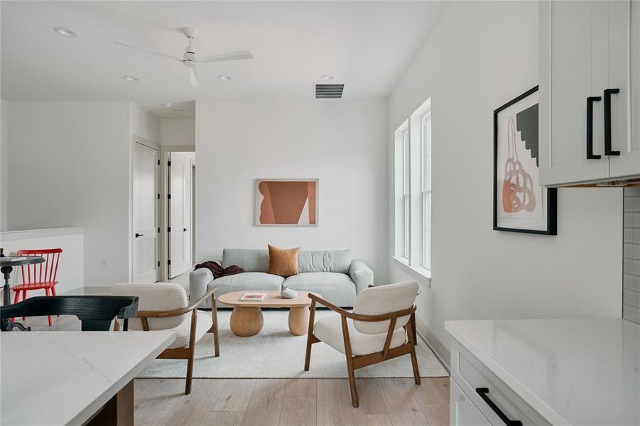 Living area featuring light wood-finish flooring, white walls, and recessed lighting