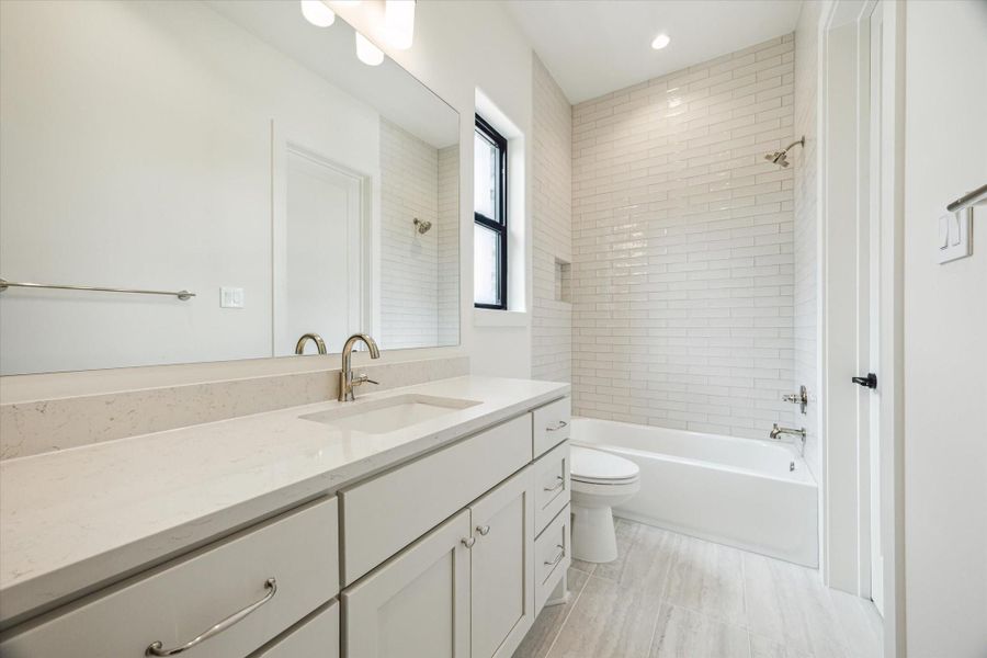 En-suite bath - has shower/tub combo and quartz countertop.