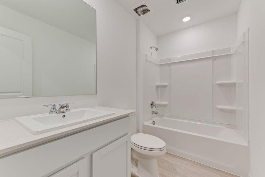 Bathroom with bathtub / shower combination, toilet, wood finished floors, vanity, and visible vents