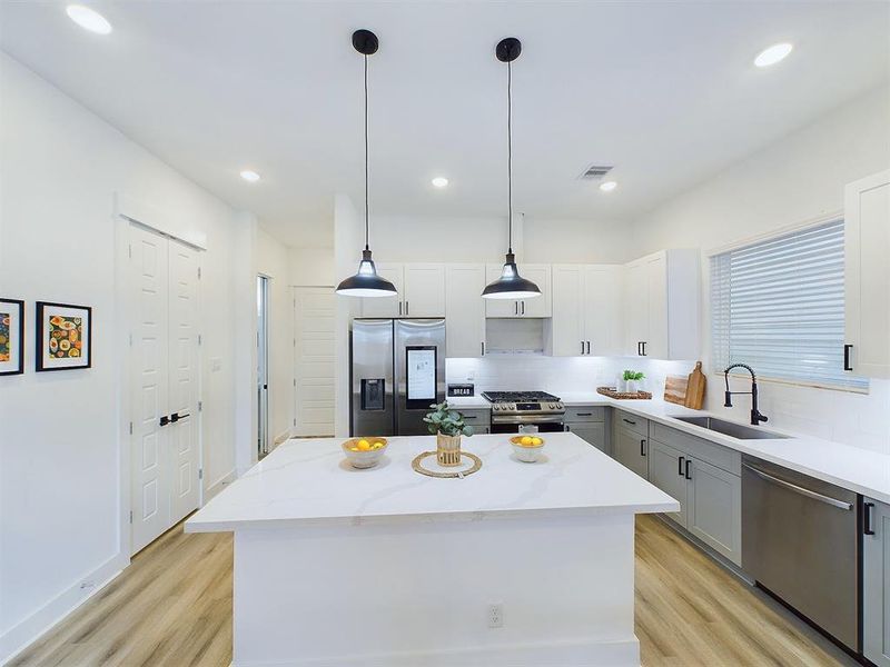 The kitchen offers  quartz countertops, stainless steel appliances, recessed lighting, and shaker cabinets and hardware with under cabinet lighting.