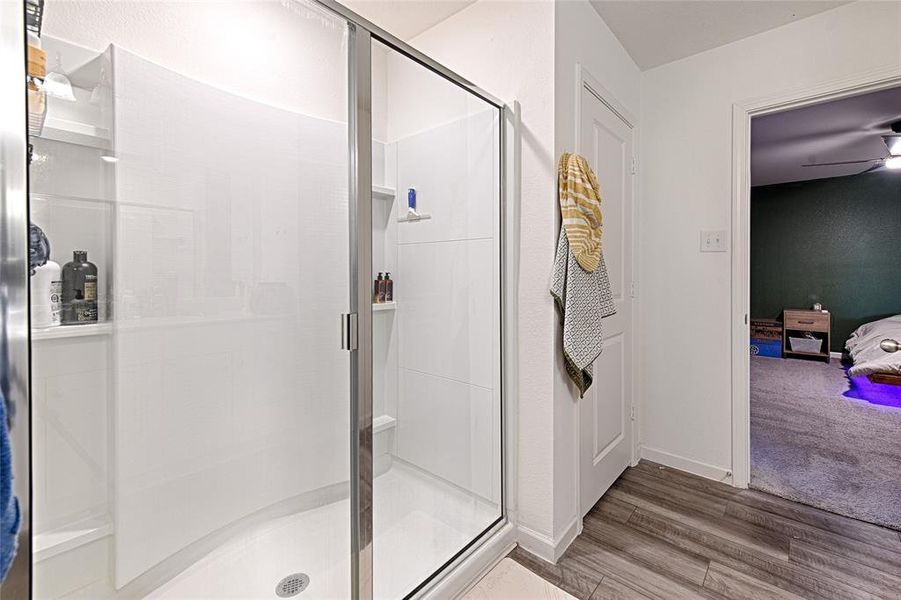 Bathroom with a shower stall, ensuite bathroom, light wood-style flooring, and a ceiling fan Bathroom with a shower stall, ensuite bathroom, light wood-style flooring, and a ceiling fan