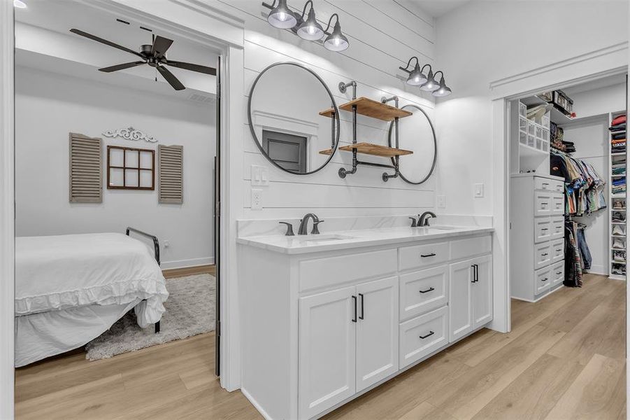 Primary bath featuring double vanity, custom walk-in closet, light wood-type flooring and shiplap walls. Primary bath featuring double vanity, custom walk-in closet, light wood-type flooring and shiplap walls.