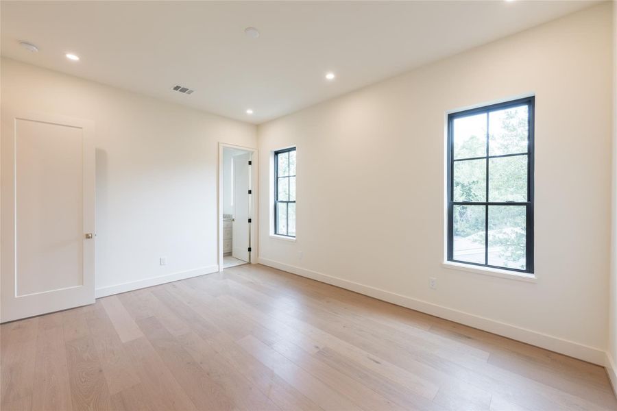 This secondary bedroom offers serene treetop views through black-framed windows and features wide plank flooring for a cohesive, elevated feel. An en-suite bath adds comfort and convenience for guests or family. This secondary bedroom offers serene treetop views through black-framed windows and features wide plank flooring for a cohesive, elevated feel. An en-suite bath adds comfort and convenience for guests or family.