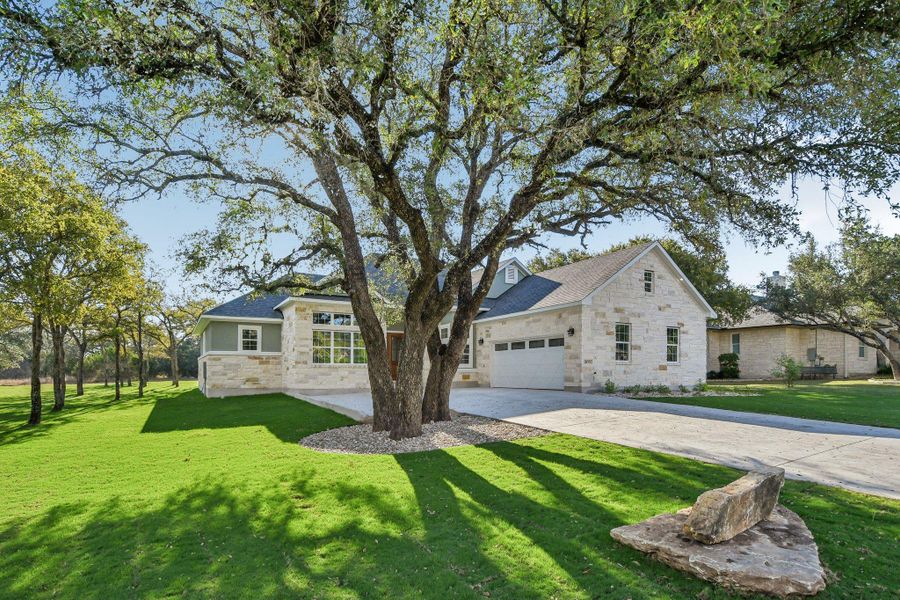 View of front of property featuring stone siding, a front yard, and driveway