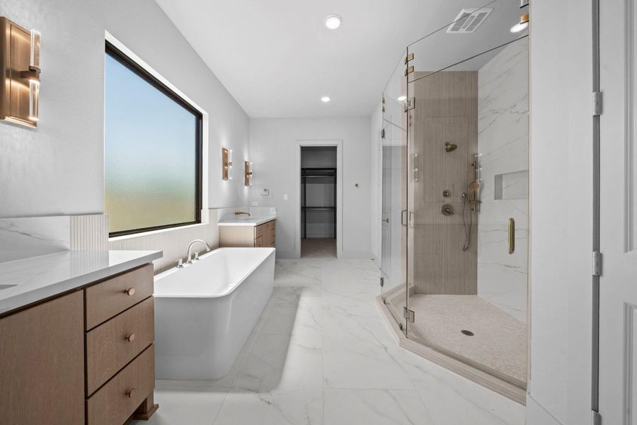 Primary bath showcasing the oversized walk-in shower, soaking tub, and refined finishes.