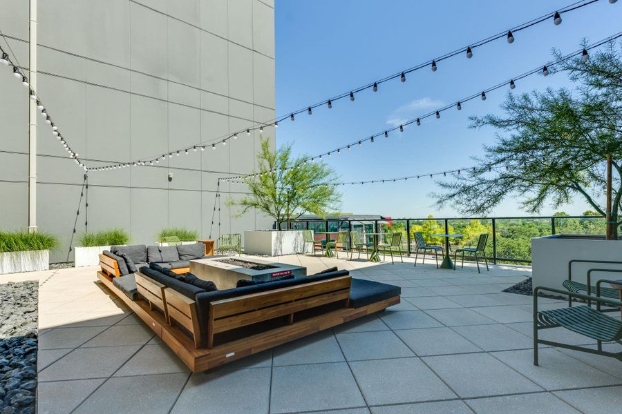Expansive outdoor patio area featuring string lighting, a fire pit, and ample seating options