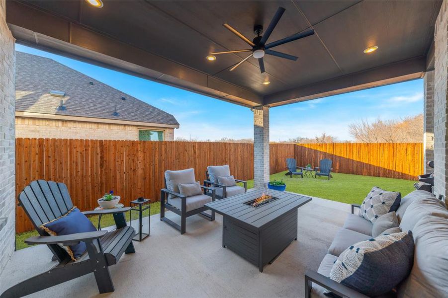 View of patio / terrace with a fenced backyard, ceiling fan, and an outdoor living space with a fire pit