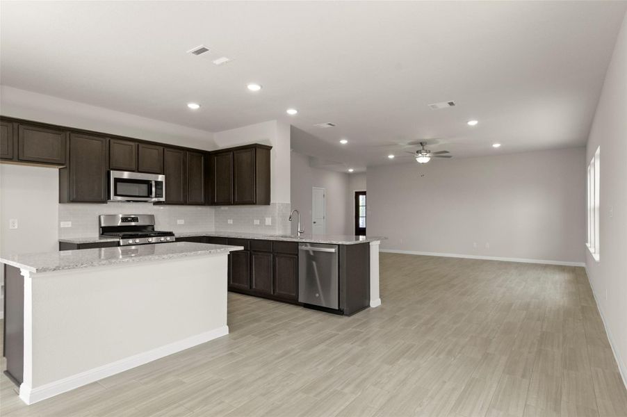 Kitchen featuring stainless steel appliances, tasteful backsplash, dark brown cabinets, recessed lighting, and a peninsula