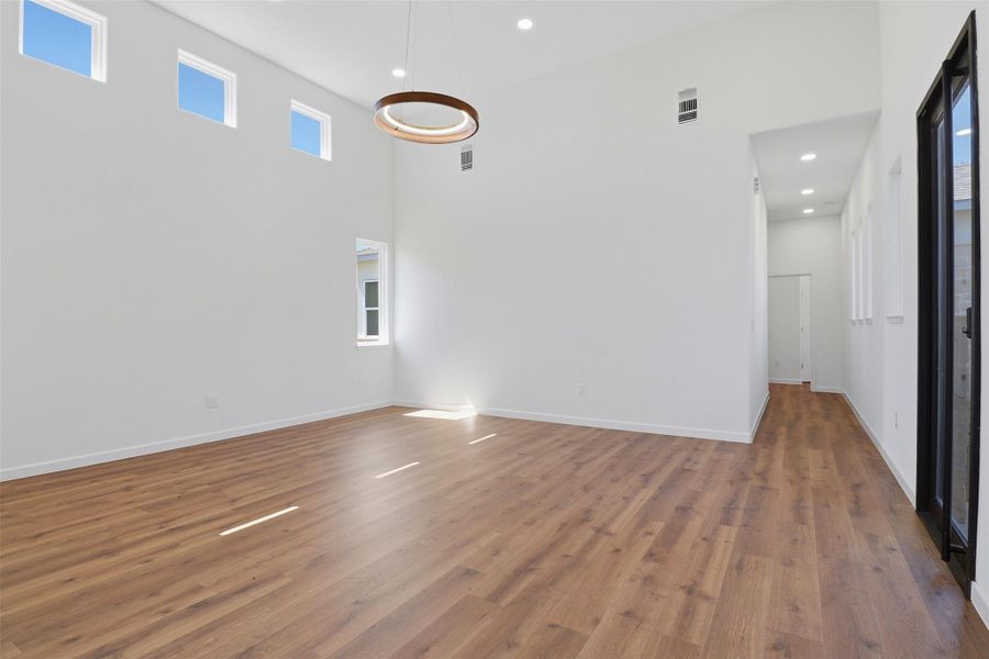 Spacious room featuring wood-finish flooring and a high vaulted ceiling Spacious room featuring wood-finish flooring and a high vaulted ceiling