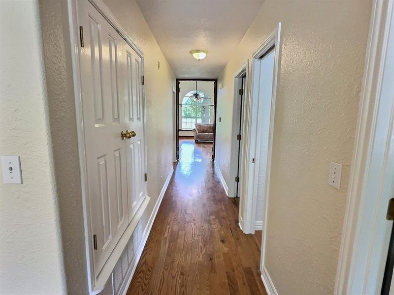 Corridor with a textured wall and dark wood-style flooring