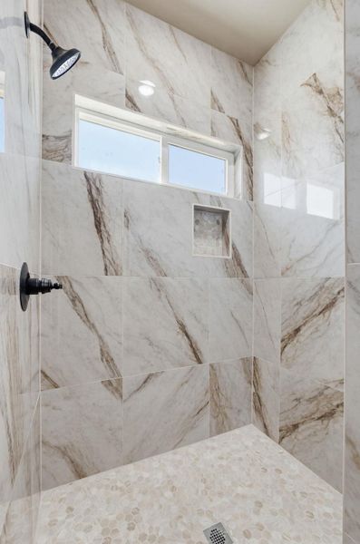 Bathroom featuring a marble finish shower and healthy amount of natural light