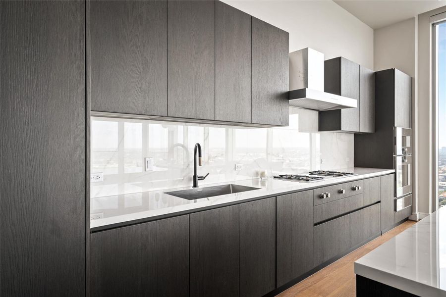Luxury kitchen sophistication with warm brown cabinetry and elegant porcelain countertops, featuring Gaggenau appliances, a gas cooktop, and induction range.