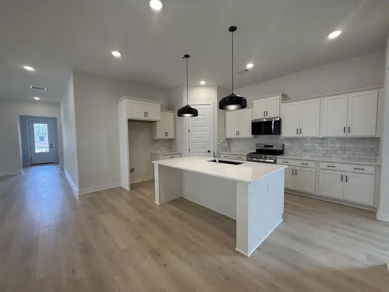 Kitchen featuring white cabinetry, stainless steel appliances, a kitchen island with sink, and light wood finished floors