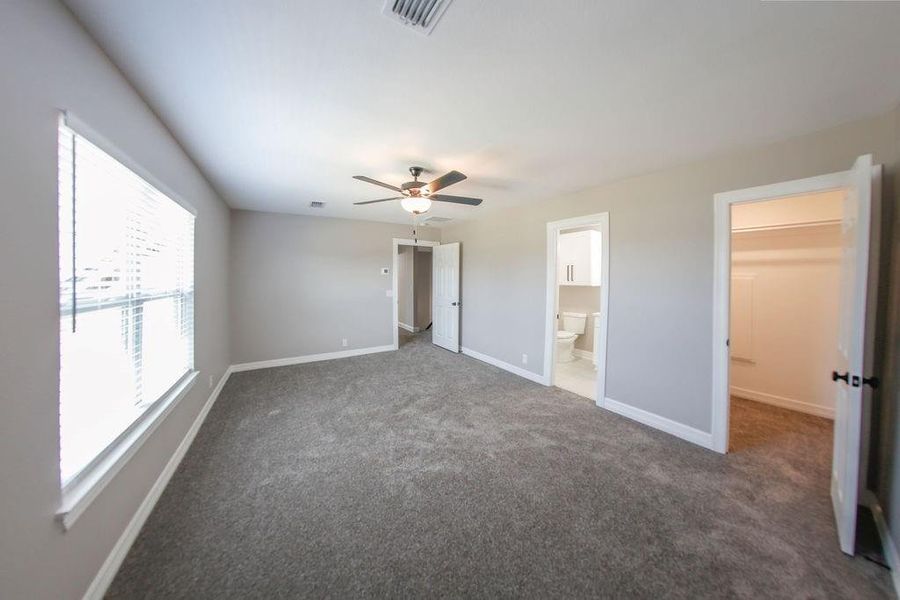 Unfurnished bedroom featuring carpet floors, a spacious closet, and a ceiling fan Unfurnished bedroom featuring carpet floors, a spacious closet, and a ceiling fan