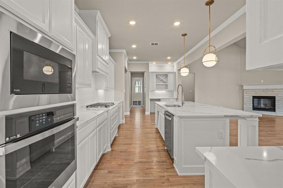 Kitchen with appliances with stainless steel finishes, white cabinetry, open floor plan, light wood-type flooring, and recessed lighting