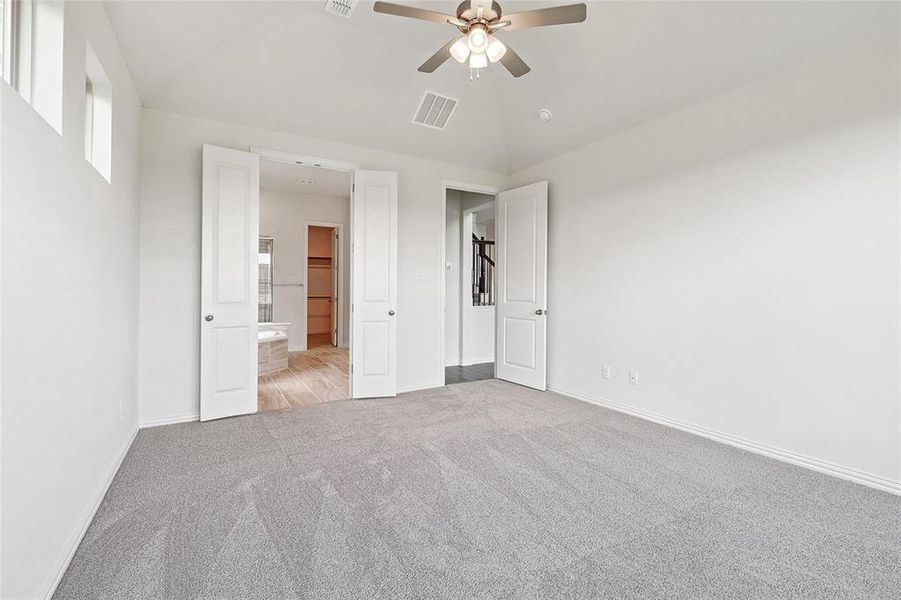 Unfurnished bedroom featuring ensuite bathroom, ceiling fan, and light colored carpet