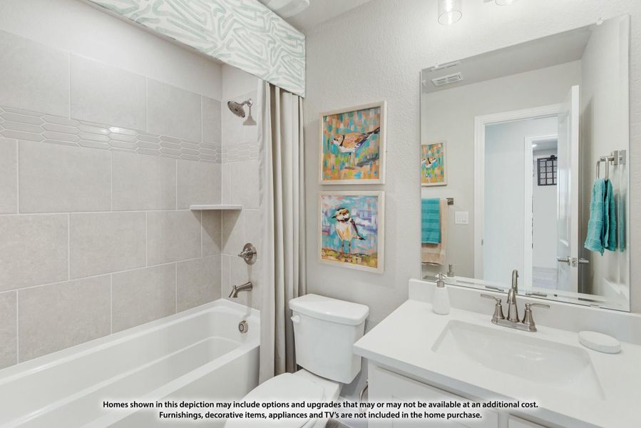 Bathroom with tiled tub and shower, white vanity, toilet, and colorful bird artwork on the walls. Bathroom with tiled tub and shower, white vanity, toilet, and colorful bird artwork on the walls.