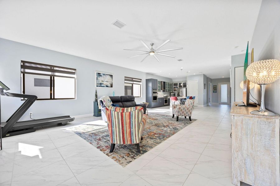 Living area featuring a ceiling fan and light marble finish flooring
