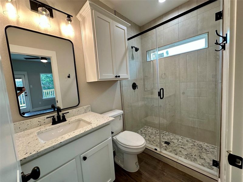 Full bath with plenty of natural light, vanity, wood finished floors, and a stall shower
