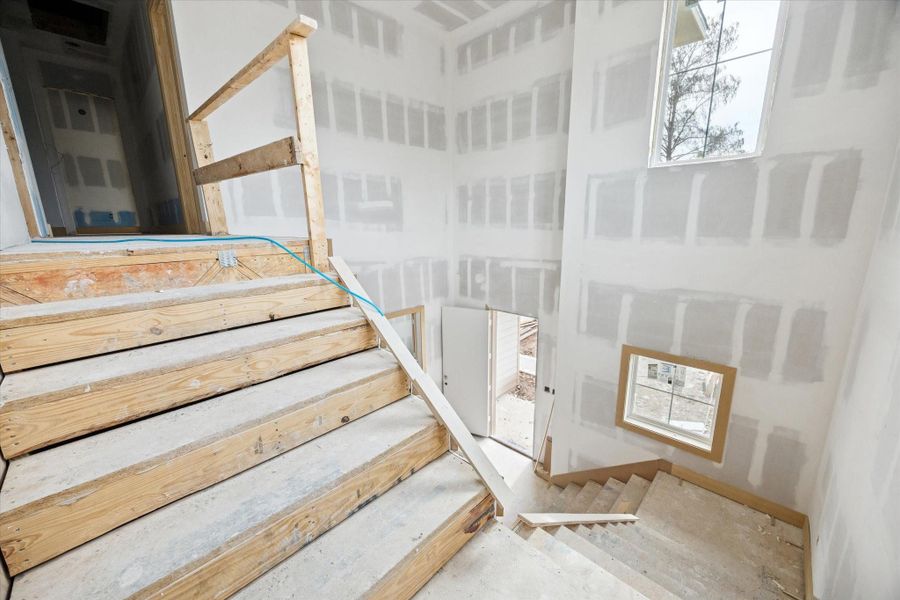 An open stairwell creates a dramatic visual connection between floors, enhanced by tall ceilings and well placed windows that draw in natural light. Architectural presence carries through the core of the home while maintaining an open, airy feel.