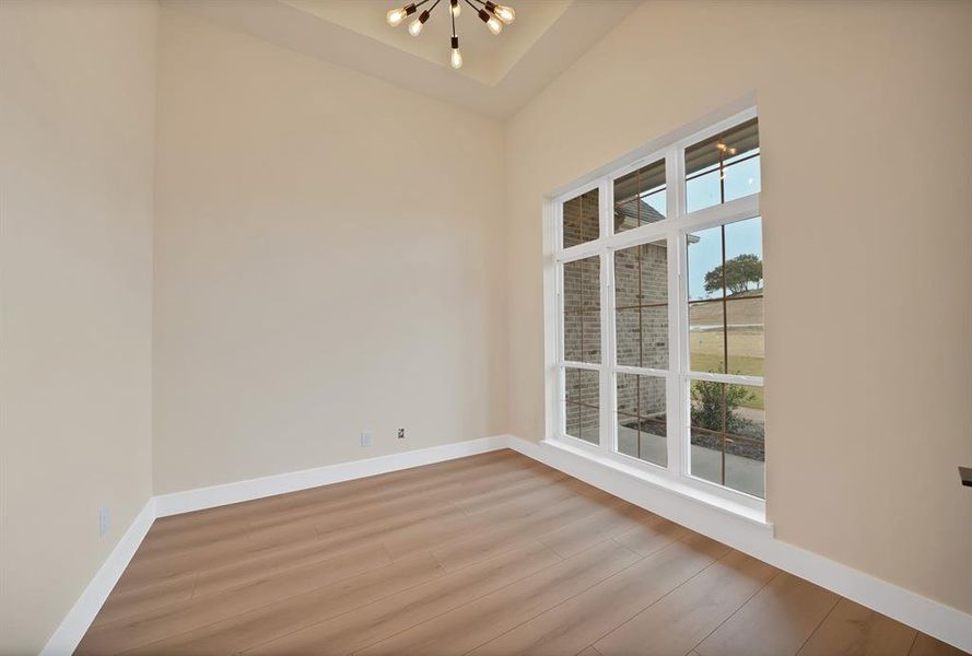 Spare room featuring wood finished floors and a chandelier Spare room featuring wood finished floors and a chandelier