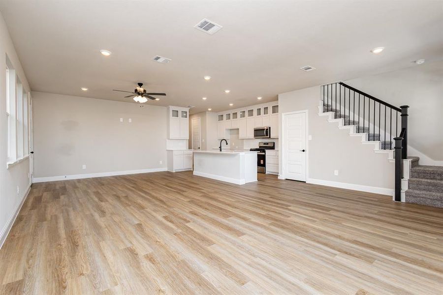Unfurnished living room with stairs, recessed lighting, light wood-style flooring, and ceiling fan