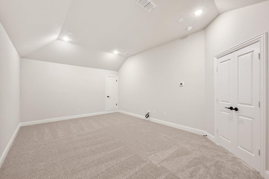 Empty room with vaulted ceiling, gray carpet, white walls, and recessed lighting Empty room with vaulted ceiling, gray carpet, white walls, and recessed lighting